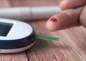 A close-up of a finger prick and blood glucose monitor for diabetes testing.
