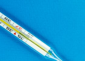Close-up of a mercury thermometer on a blue background captured in a studio setting.